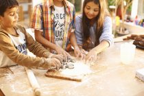 Діти ріжуть форми в тісто на кухні — стокове фото