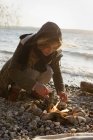 Mujer haciendo un fuego a orillas del mar - foto de stock