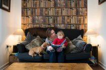 Mãe leitura de livro para filho no sofá — Fotografia de Stock