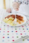 Tiro cortado da criança fêmea comendo ravioli à mesa — Fotografia de Stock