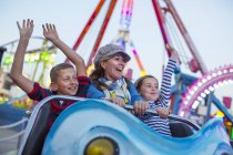 Mature woman with son and daughter on fairground ride — Stock Photo