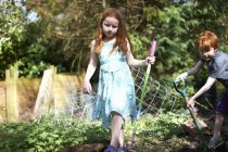 Due bambini piccoli in giardino, con attrezzi da giardinaggio — Foto stock
