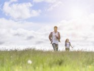 Подростковая пара бежит по лугу под ярким солнцем — стоковое фото