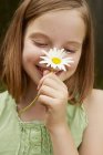 Portrait of girl in garden holding up daisy — Stock Photo