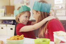 Sisters in paper crowns hugging at Christmas party — Stock Photo