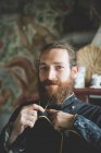 Портрет бородатого мужчины среднего возраста, застегивающего глиняную куртку, смотрящего на камеру улыбающегося — стоковое фото