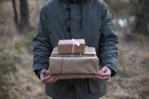 Recortado tiro de regalos que se llevan a través del bosque por el hombre joven - foto de stock