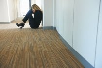 Reife Frau sitzt gegen Wand im Flur — Stockfoto