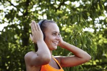 Jovem corredor feminino ajustando fones de ouvido — Fotografia de Stock