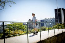 Jeune homme skateboard le long de la passerelle — Photo de stock
