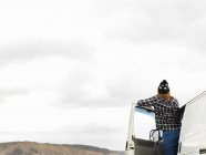 Rear view of young woman looking out from camper van — Stock Photo