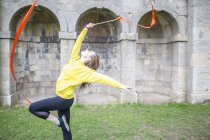 Молода жінка практикує стрічковий танець, настінні арки на фоні — стокове фото