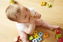 Baby boy biting on building block — Stock Photo