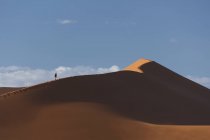 Silhouette eines Mannes beim Wandern auf einer riesigen Sanddüne — Stockfoto