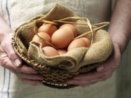 Femme âgée tenant des œufs en tissu vintage et panier — Photo de stock