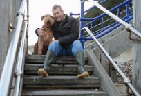 Портрет пожилого человека с собакой, сидящей на ступеньках — стоковое фото