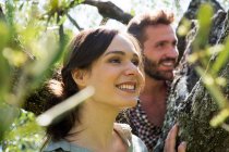 Молода пара в дереві дивиться геть усміхнений — стокове фото