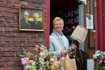 Reife Kundin trägt Lampe und Einkaufstasche vor Vintage-Geschäft — Stockfoto