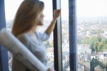 Female architect gazing from office window at Brussels cityscape, Belgium — Stock Photo