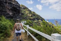 Rückansicht eines jungen männlichen Touristen, der in Richtung Leuchtturm von Makapuu läuft, Oahu, Hawaii, USA — Stockfoto