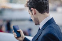 Над переглядом плеча бізнесмена смс на смартфон — стокове фото