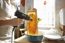 Пчеловод на кухне плавит воск на раме из меда — стоковое фото