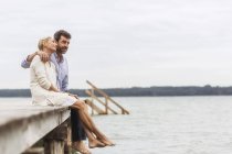 Couple d'âge mûr assis sur le bord de la jetée, détente — Photo de stock