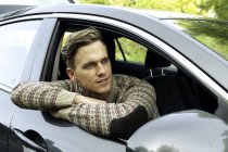 Young man leaning and looking out from car window — Stock Photo