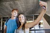 Молодая пара фотографирует себя с помощью телефона — стоковое фото