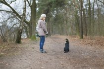 Femme adulte moyenne et son chien en forêt — Photo de stock