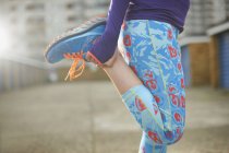 Обрезанный вид женщины, согнувшей ногу и растянувшейся перед упражнениями — стоковое фото