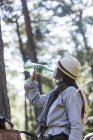 Mature woman cyclist drinking from water bottle in forest — Stock Photo