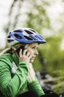 Young female cyclist chatting on smartphone, Augsburg, Bavaria, Germany — Stock Photo