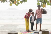 Пара и сын выбирают одежду из тротуара, пляж Ипанема, Рио-де-Жанейро, Бразилия — стоковое фото