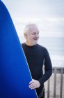 Porträt eines älteren Mannes mit Surfbrett am Strand — Stockfoto