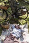 Зріла жінка-підробка відпочиває на ковдрі в лісі розмовляє на смартфоні — стокове фото