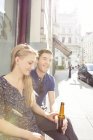 Молода пара на тротуарному кафе п'є пиво — стокове фото