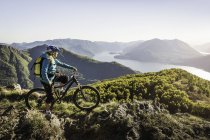 Giovane donna in mountain bike, vista lago di Como, Italia — Foto stock