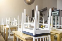 Upside down chairs on tables in closed cafe interior — Stock Photo