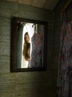 Mirror reflection of teenage girl peering from bedroom doorway — Stock Photo