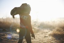 Mann trägt Baumstamm in ländlicher Landschaft — Stockfoto