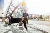 Бізнесмен з колісною валізою, що йде ескалатором — стокове фото