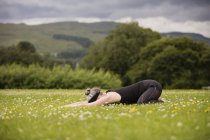 Mature woman practicing yoga childs position in field — Stock Photo