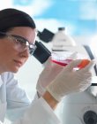 Bióloga feminina detentora de frasco contendo células estaminais, cultivadas em meio de crescimento vermelho — Fotografia de Stock