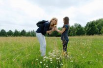 Madre e figlia che odorano di fiori selvatici nel campo — Foto stock