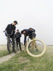 Ciclisti urbani che controllano gli pneumatici in campo — Foto stock