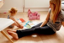 Женщина и дочь малыша играют на полу — стоковое фото