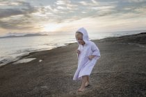 Female toddler wearing hooded robe on beach, Calvi, Corsica, France — Stock Photo