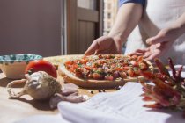 Abgeschnittenes Bild einer Frau, die in der Küche Pizza zubereitet — Stockfoto