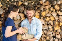 Young couple selecting chopped firewood from pile — Stock Photo
